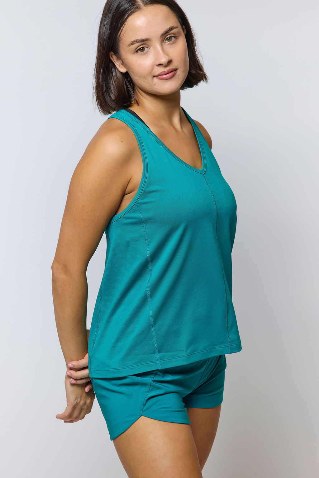Model wearing Excel Sculpt Performance Shorts and a matching top in teal color, showcasing comfort and style.