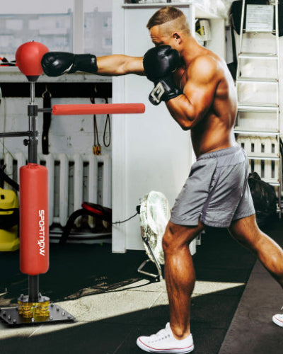 Man practicing boxing with a punching bag in a home gym setting