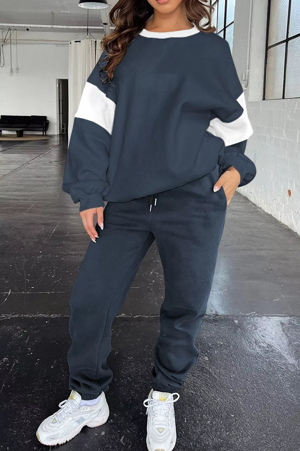 Model wearing MotionFlex Sweatshirt & Jogger Set featuring a relaxed fit in navy and white for active comfort.