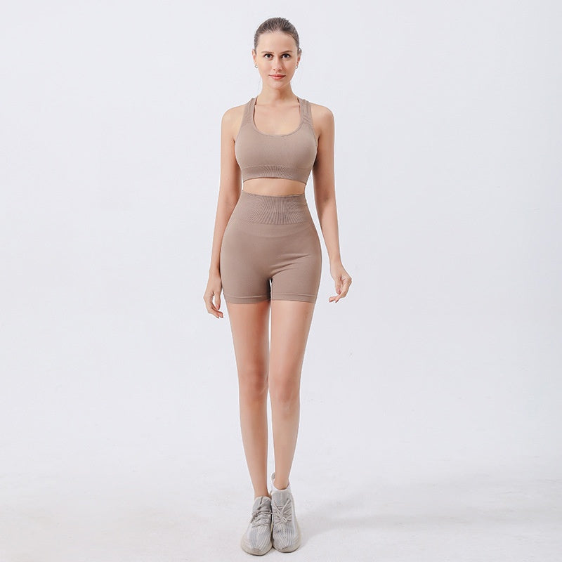 Women wearing seamless ribbed 2-piece workout sets with crop tanks and high waist shorts in stylish color-block designs for yoga and fitness