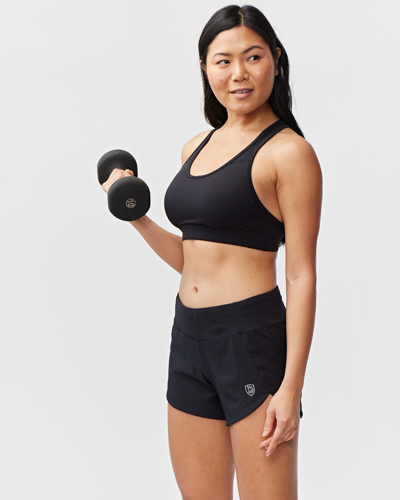 Model wearing Excel Sculpt Performance Shorts and a sports bra while holding dumbbells.