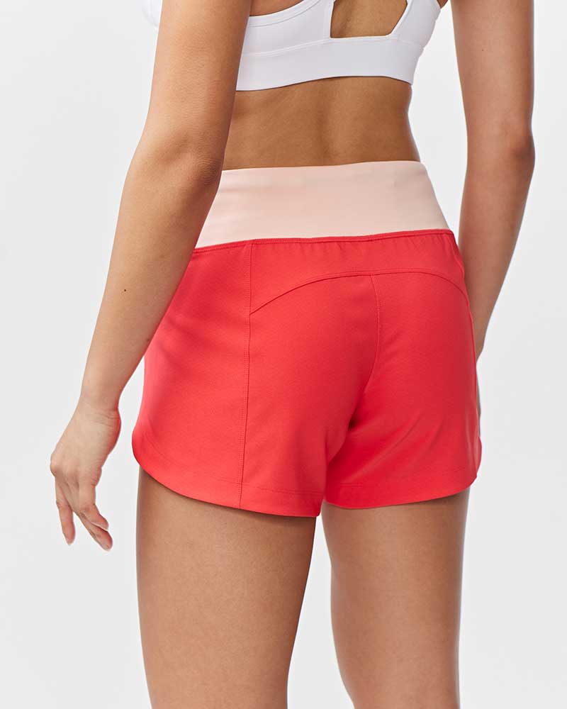 Back view of a person wearing Excel Sculpt Performance Shorts in coral with a light pink waistband.