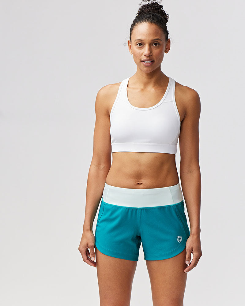Model wearing Excel Sculpt Performance Shorts with a white sports bra for activewear.