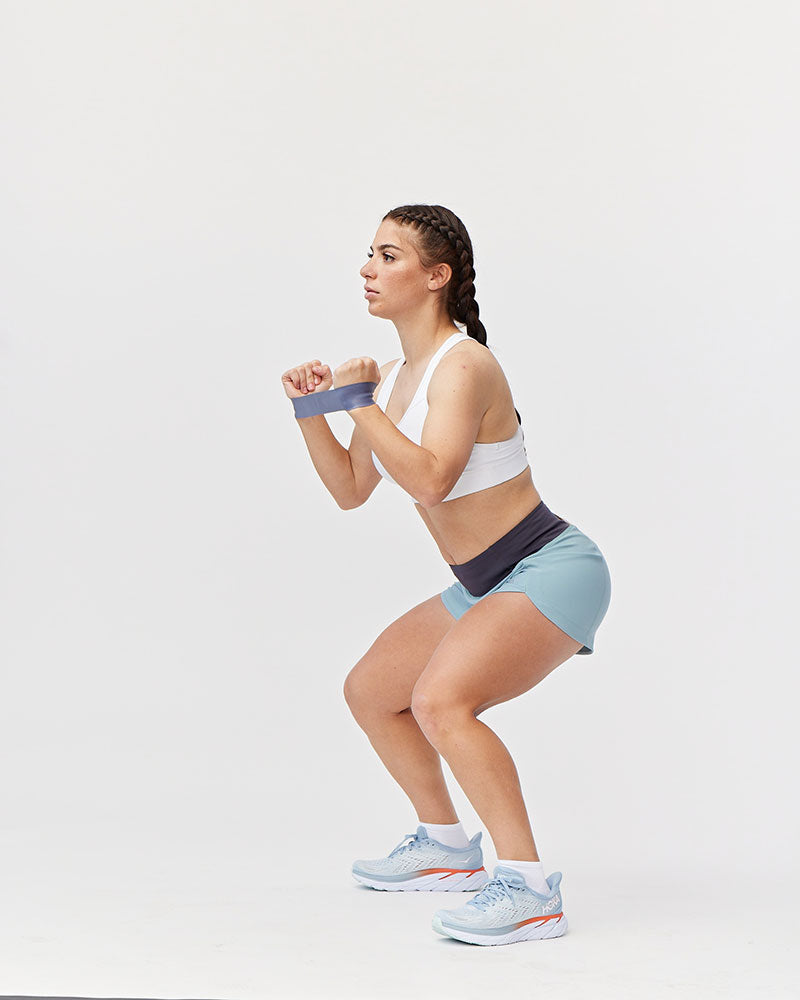 Woman performing a squat in Excel Sculpt Performance Shorts, showcasing fitness and confidence in her workout.