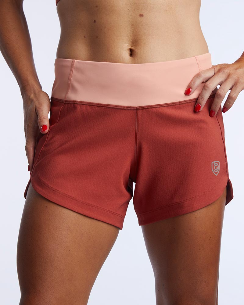 Excel Sculpt Performance Shorts in rust color with a pink waistband, designed for confident movement and style.