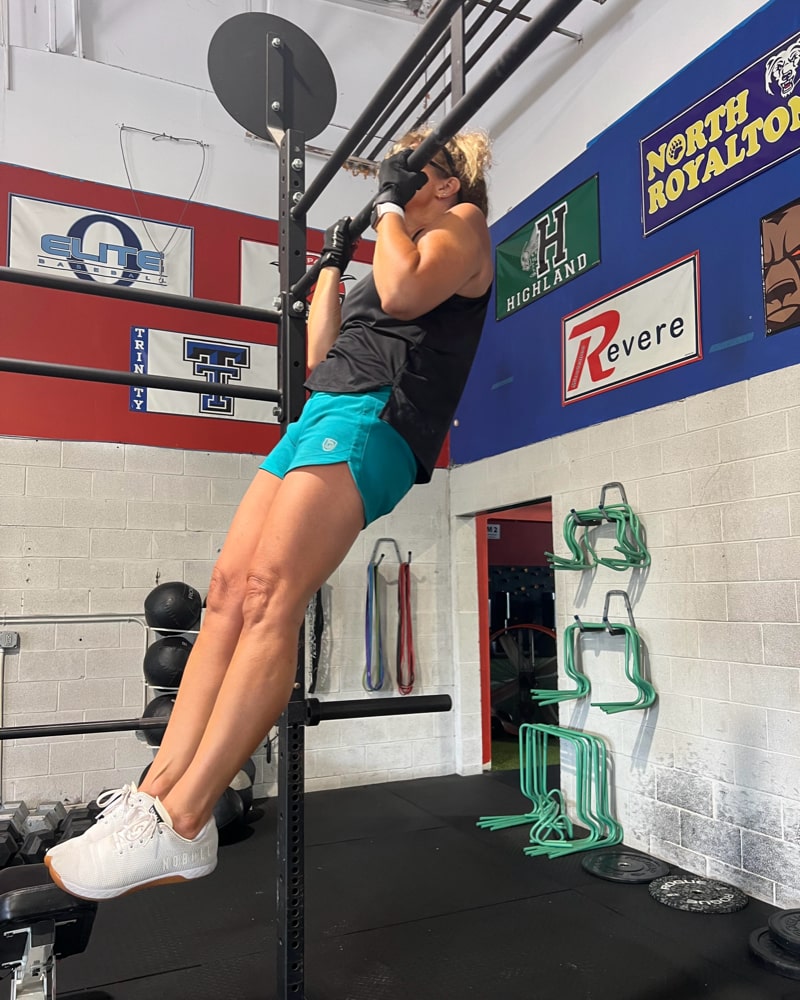 Athlete performing pull-ups in Excel Sculpt Performance Shorts in a gym setting, showcasing strength and style.