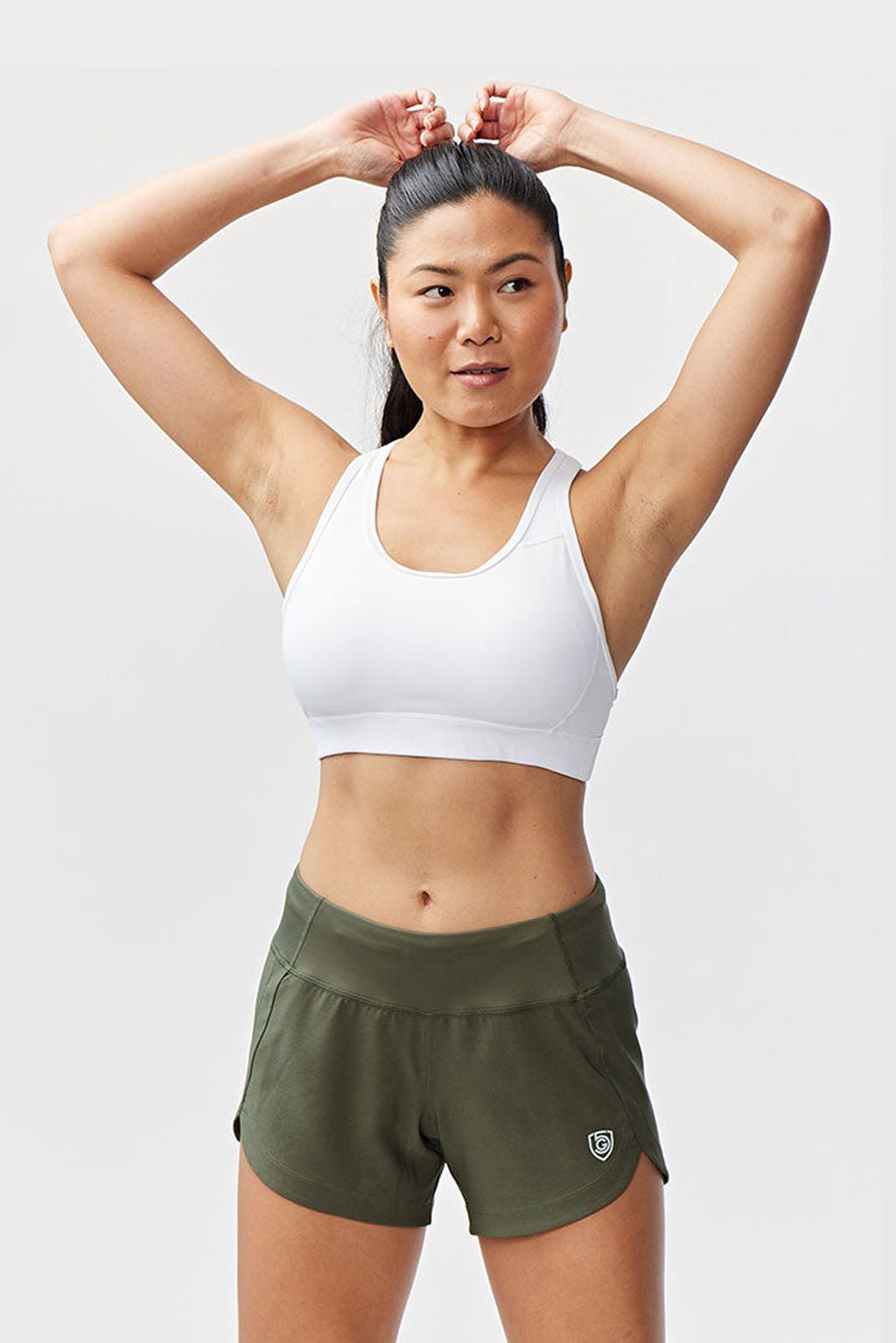 Woman wearing Excel Sculpt Performance Shorts and a white sports bra, showcasing activewear for confidence and movement.
