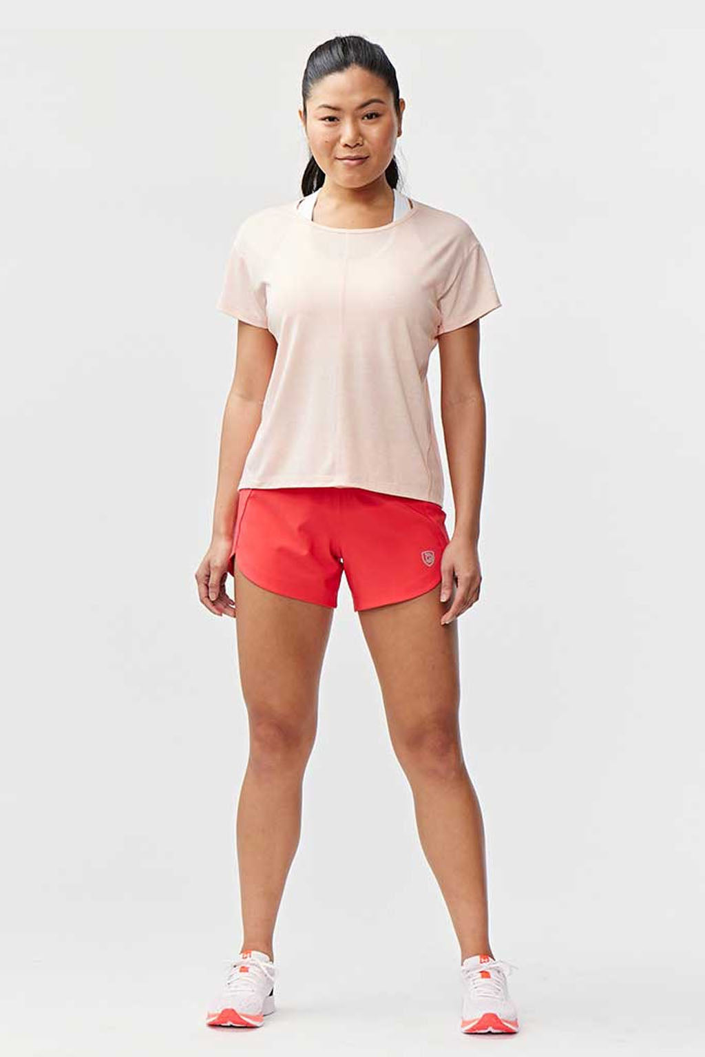 Woman wearing Excel Sculpt Performance Shorts and a light top, standing confidently in a sporty pose.