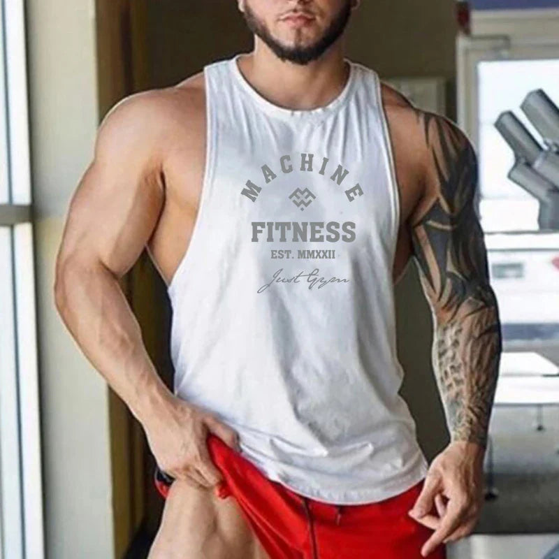 Muscular man wearing a white FlexFit workout tank in a gym, showcasing comfort and mobility for performance training.