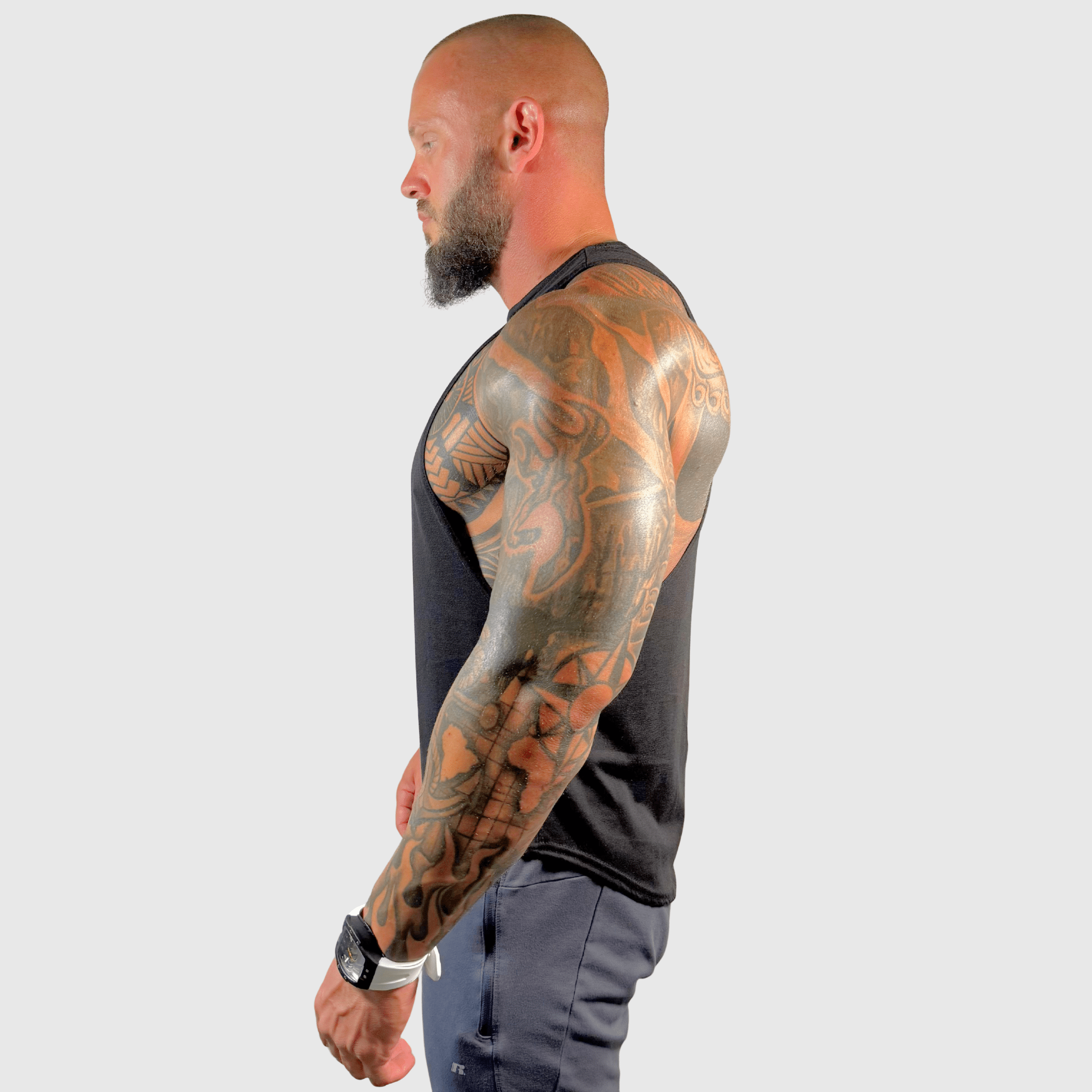 AeroFlex Drop Arm Training Tank showcased by a tattooed man in profile, highlighting athletic style and fit.
