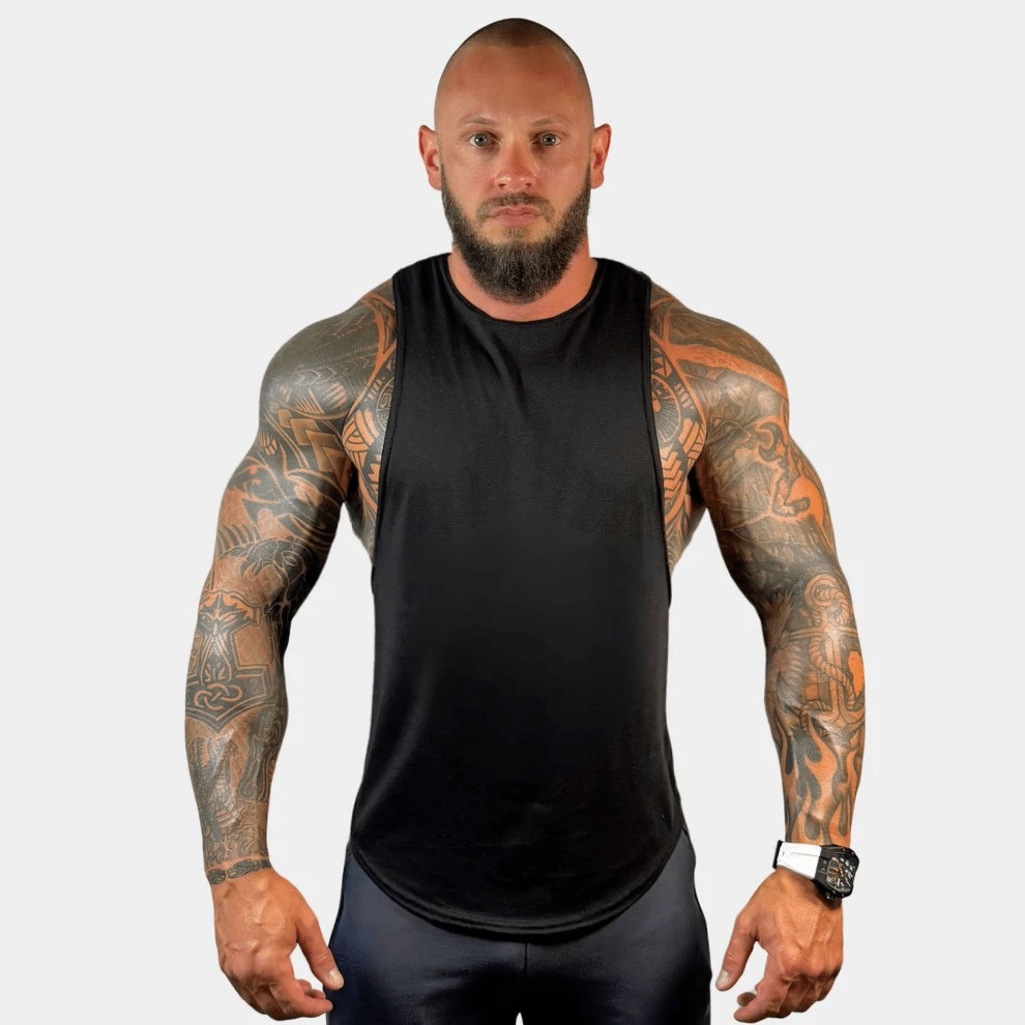 AeroFlex Drop Arm Training Tank worn by a muscular man with tattoos, showcasing a sleek, athletic look.