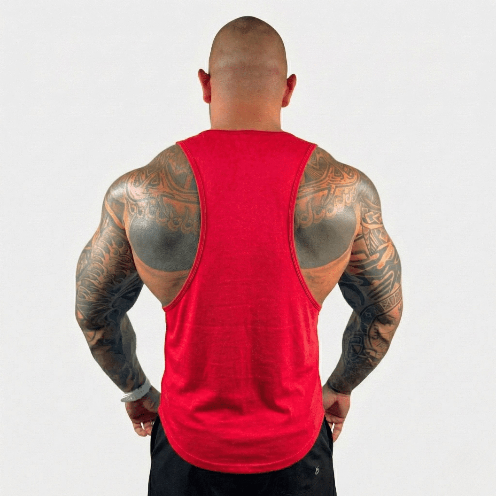 Man showcasing AeroFlex Drop Arm Training Tank from the back, revealing strong physique and tattoos.