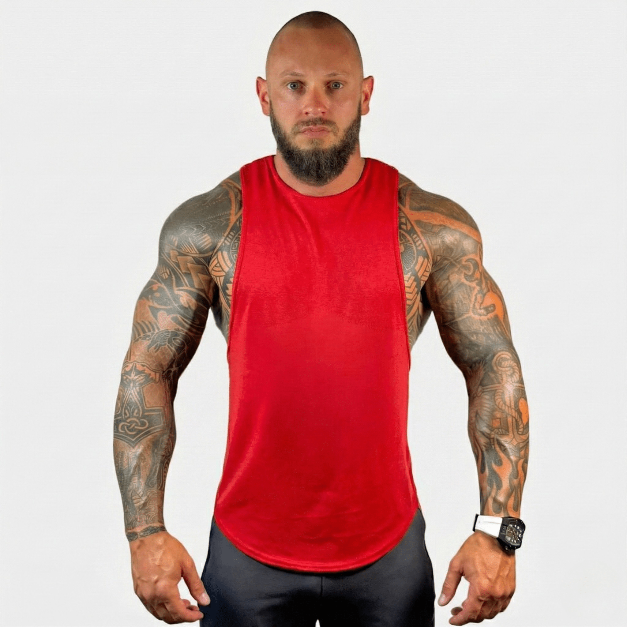 AeroFlex Drop Arm Training Tank in red, showcasing a muscular man with tattoos in a fitness setting.