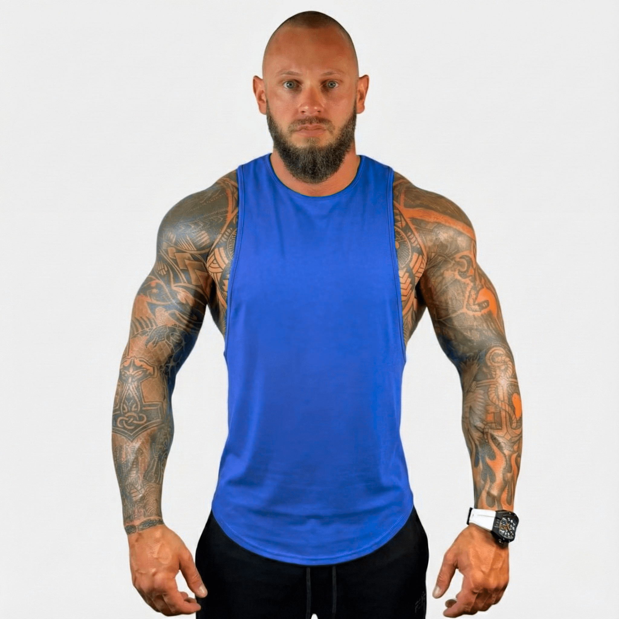 AeroFlex Drop Arm Training Tank in vibrant blue, showcased by a muscular man with tattoos, ideal for fitness enthusiasts.