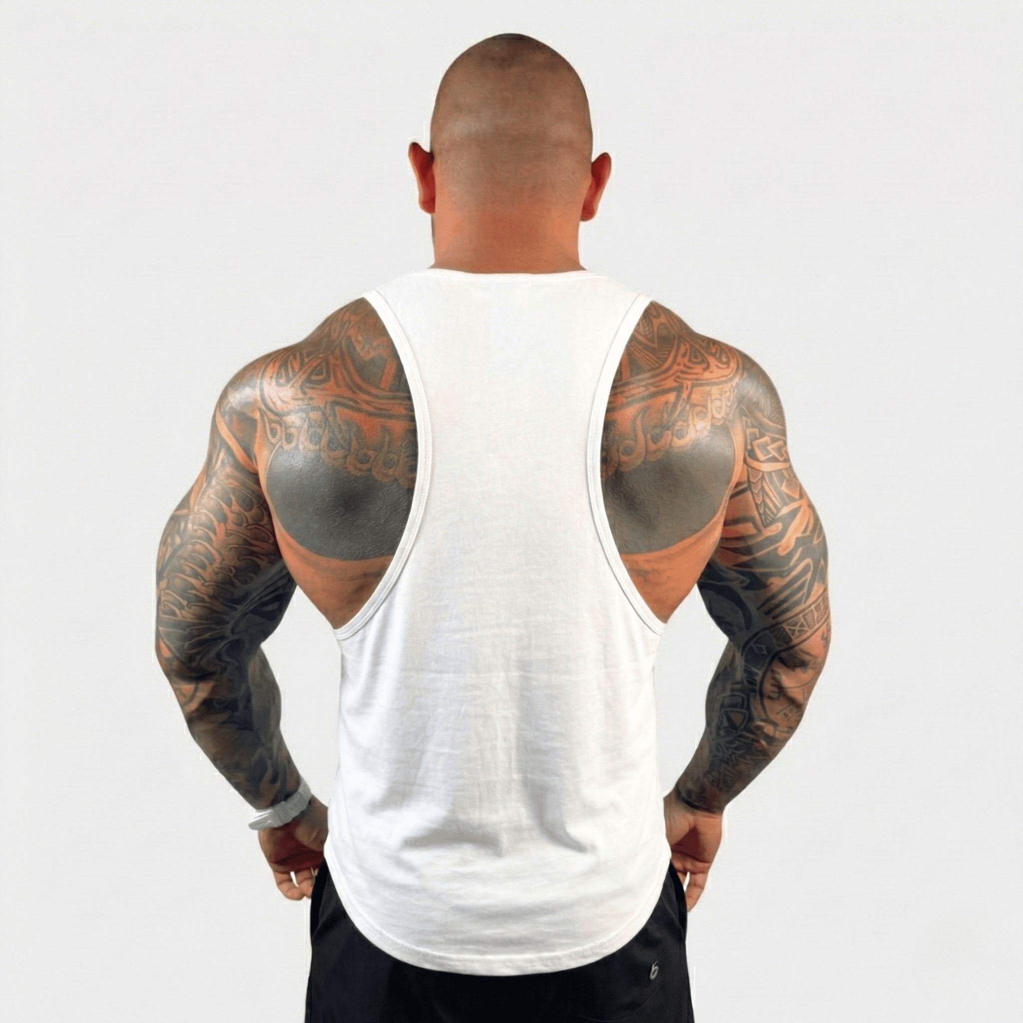 Man showcasing muscular back in AeroFlex Drop Arm Training Tank, highlighting extensive tattoos.