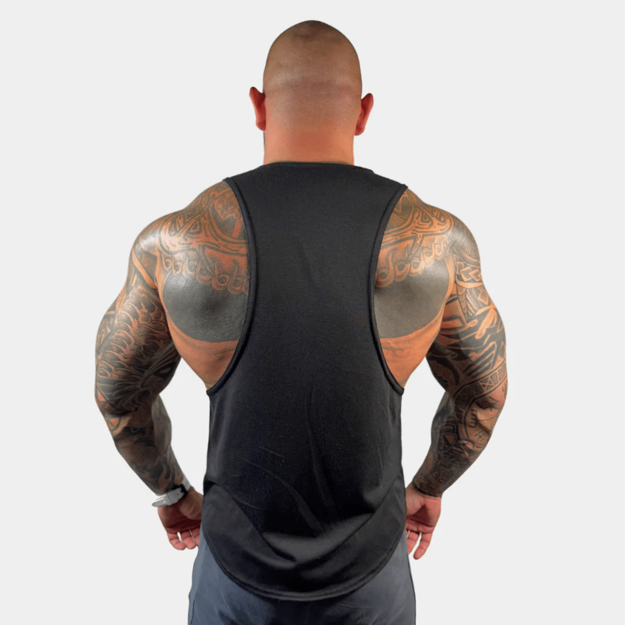 Muscular man showcasing the back view of the AeroFlex Drop Arm Training Tank, highlighting its design and fit.