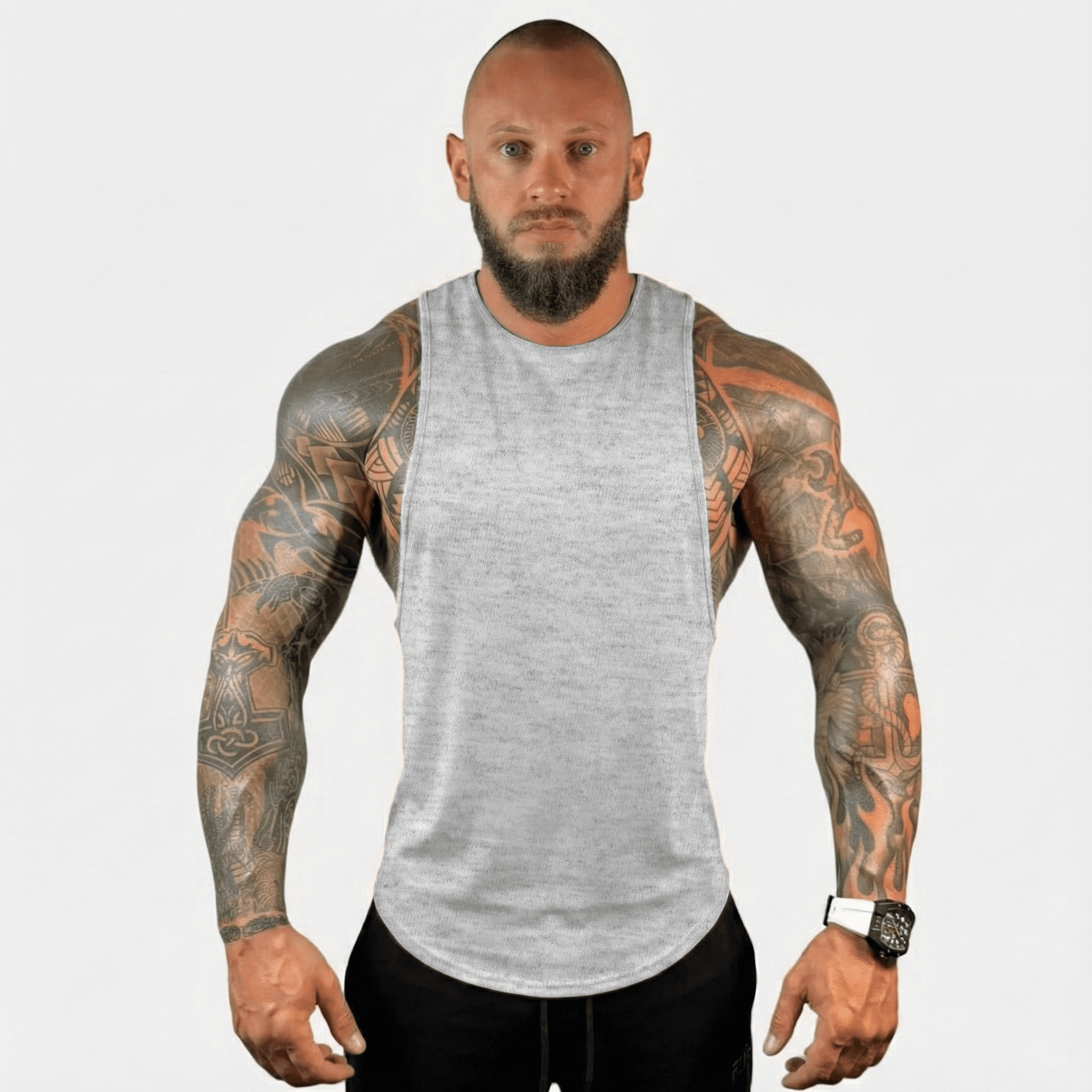 AeroFlex Drop Arm Training Tank worn by a muscular man showcasing tattooed arms, ideal for fitness enthusiasts.
