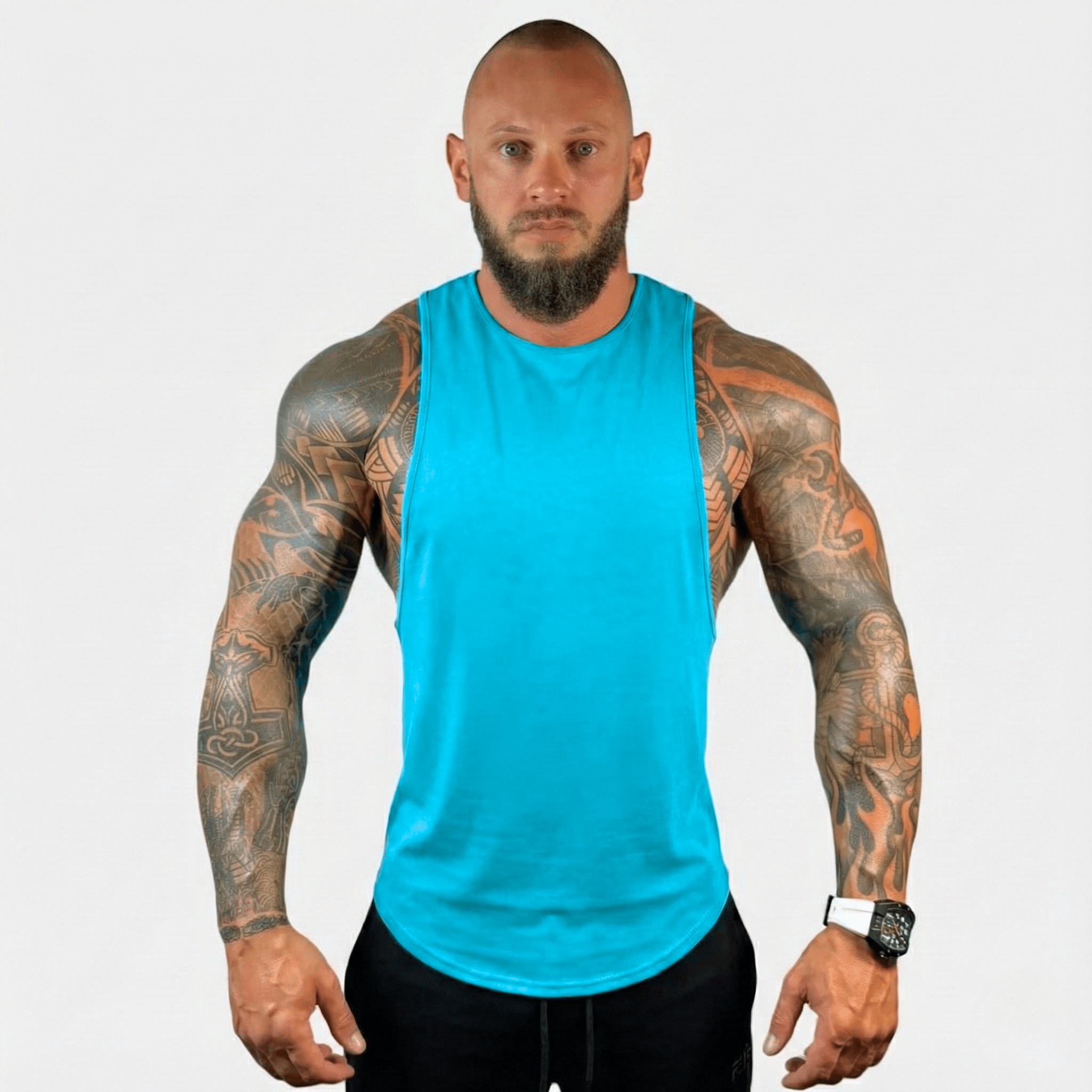 AeroFlex Drop Arm Training Tank in turquoise on a muscular model with tattoos standing against a plain background.