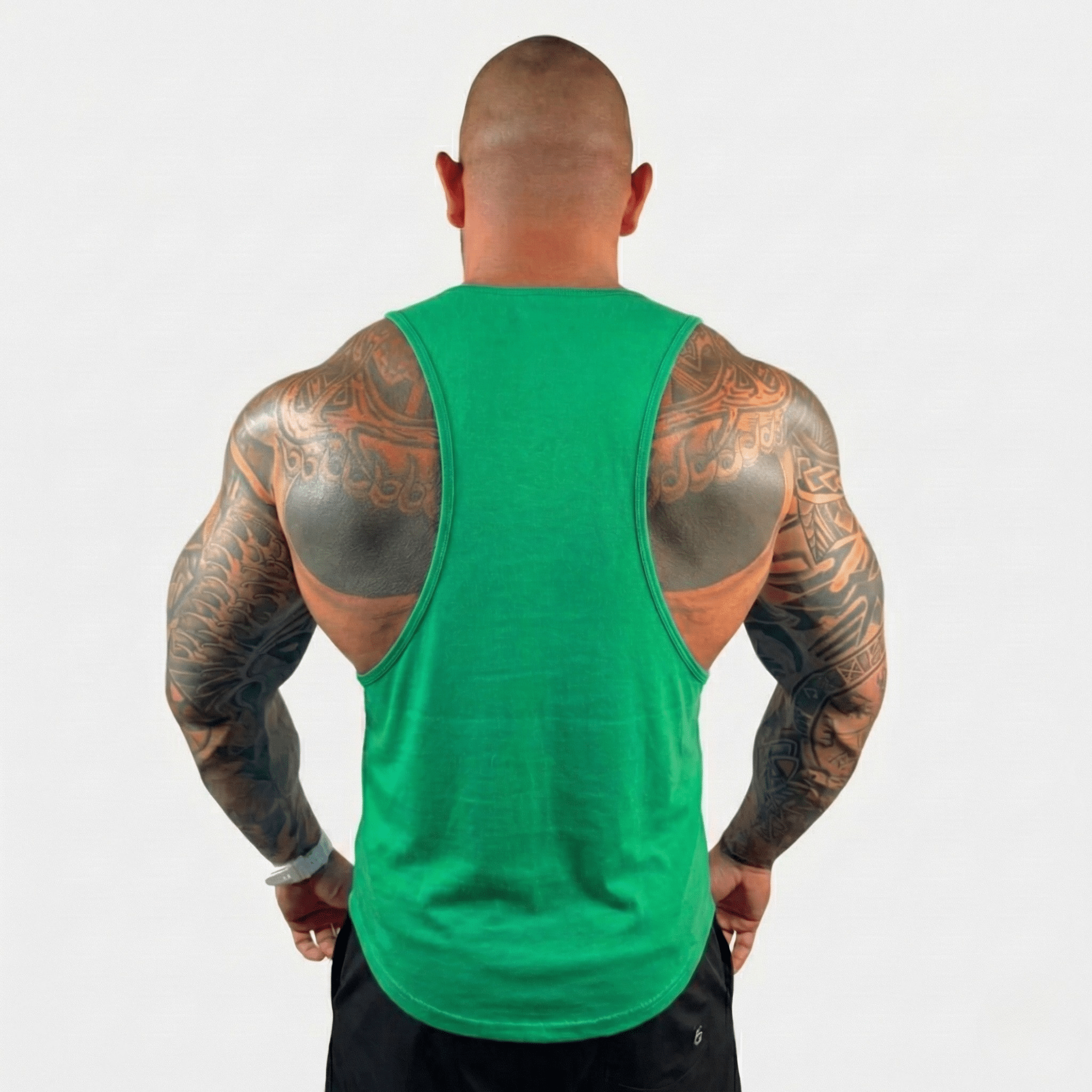 Man wearing AeroFlex Drop Arm Training Tank, showcasing muscular back and tattoos in a vibrant green color.