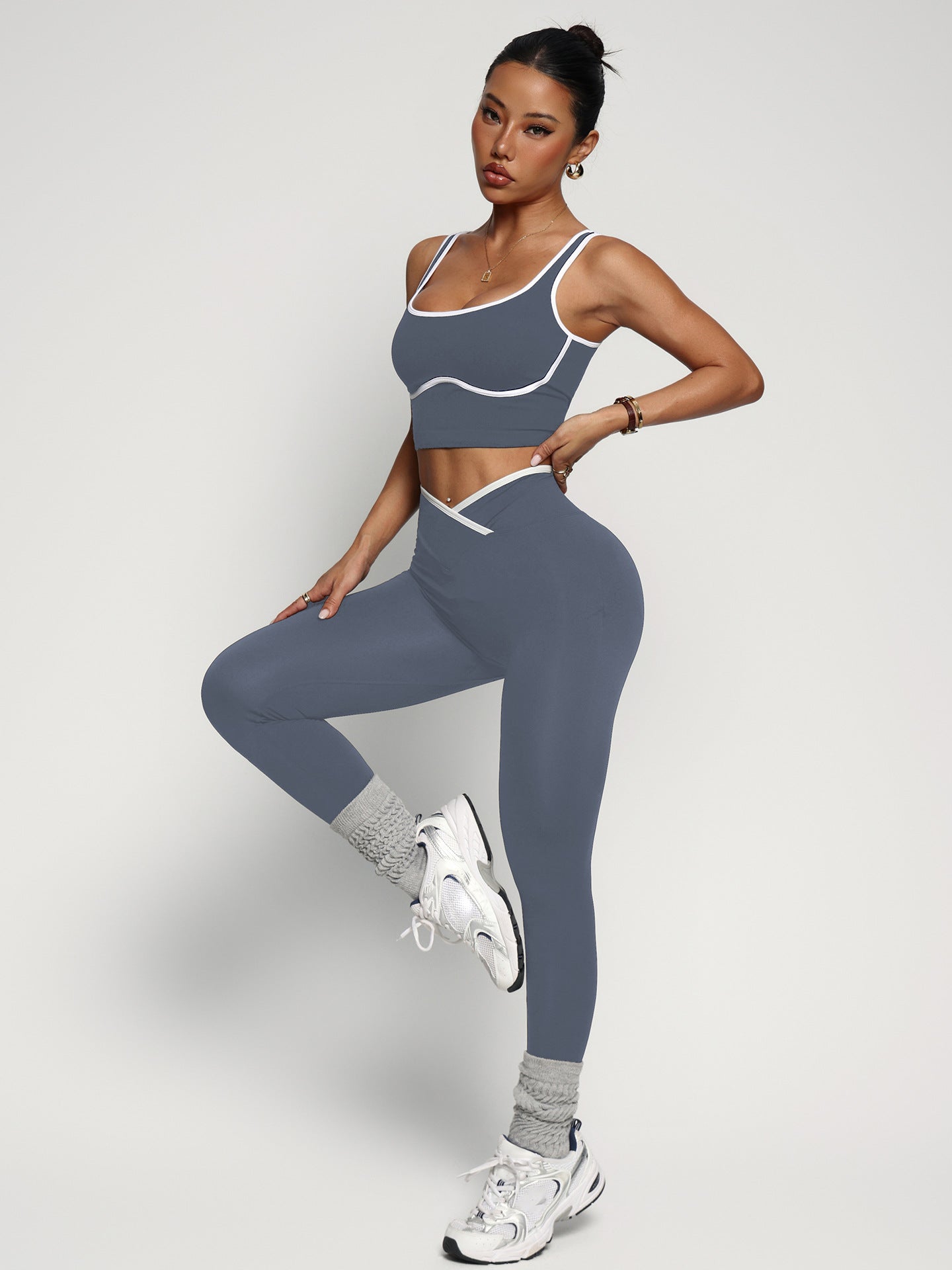 Young woman wearing women's workout outfit set with sports bra tank top and high waist yoga pants in gray color