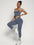 Young woman wearing women's workout outfit set with sports bra tank top and high waist yoga pants in gray color